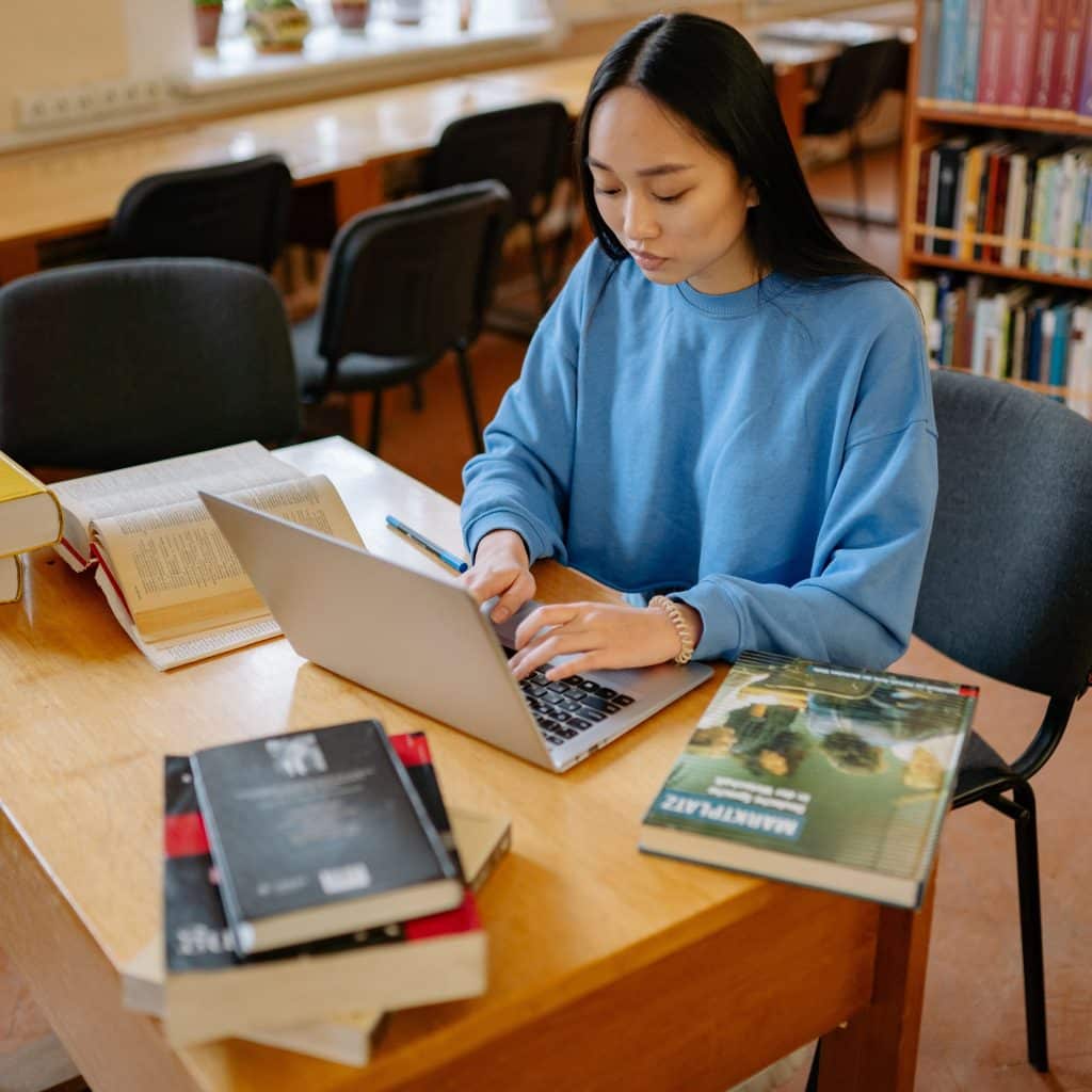 Persona revisando información en libros y un portátil